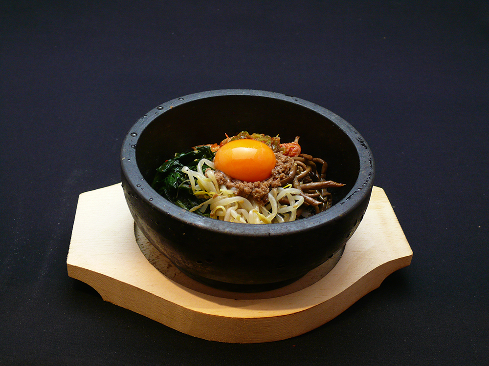 アツアツの器の中で、ナムルやキムチなどたっぷりの具とご飯を混ぜれば出来上がり。大将の韓国料理でバツグンの人気。ぜひ一度はご賞味を！